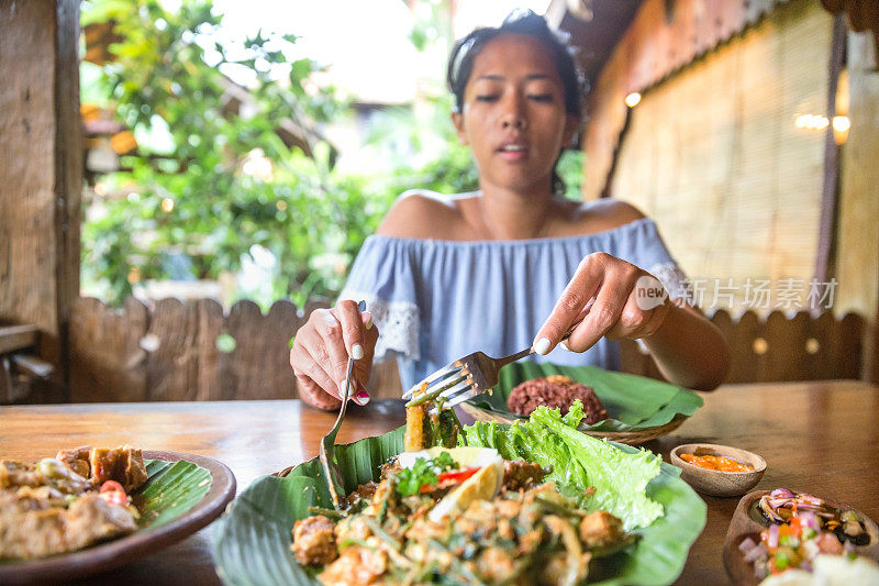 印度尼西亚妇女吃健康的素食沙拉(gado gado)